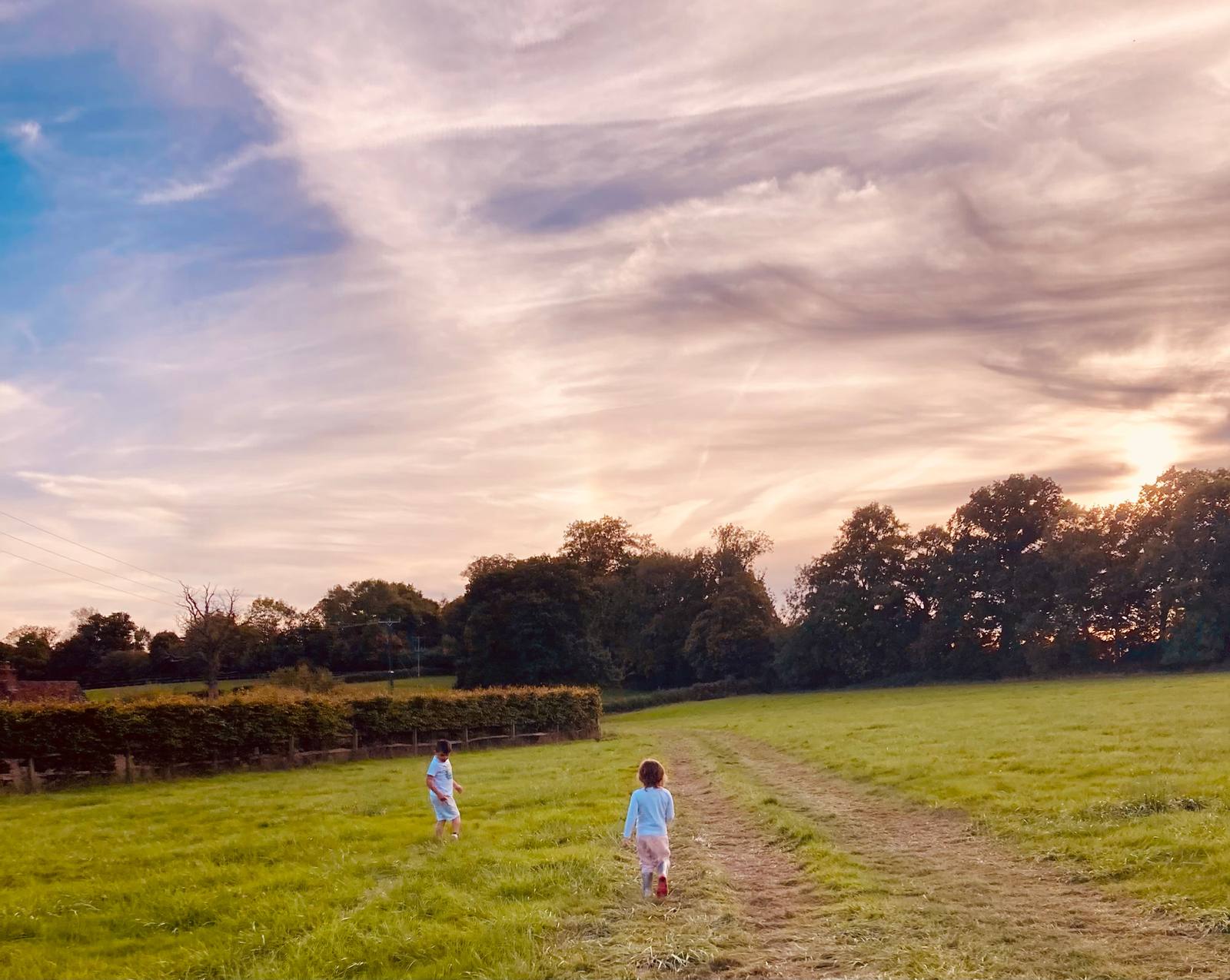 Two children walking a mown track across the camping meadow at dusk